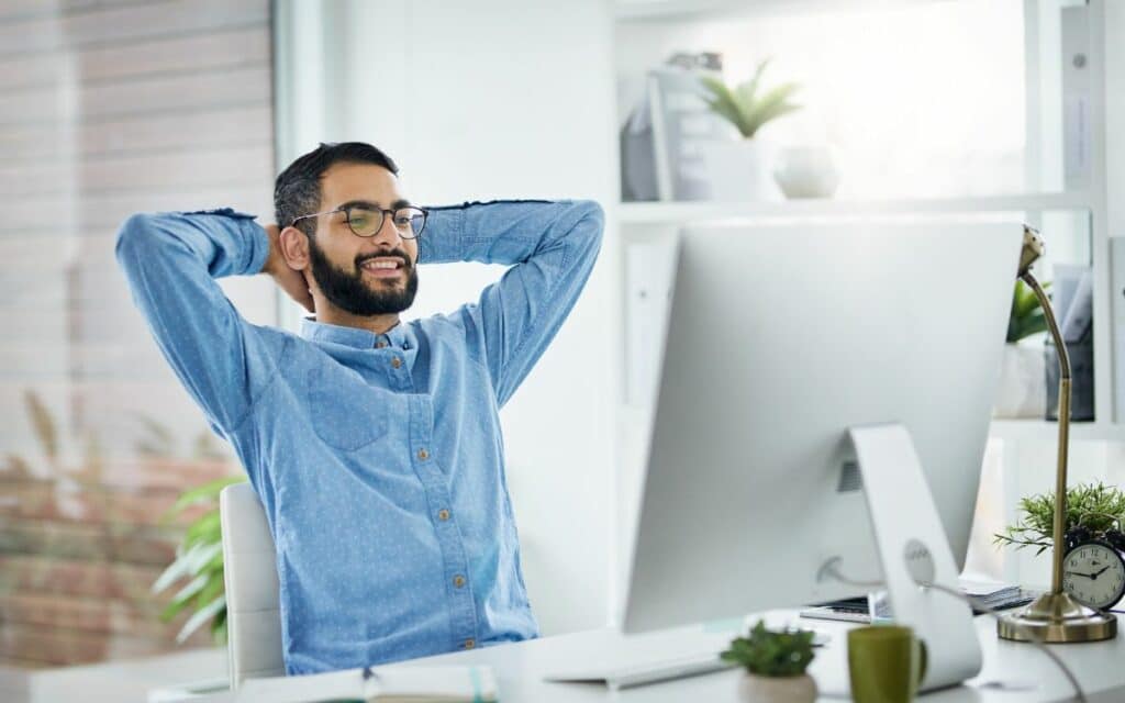 Man leaning back in his seat while looking at his computer monitor