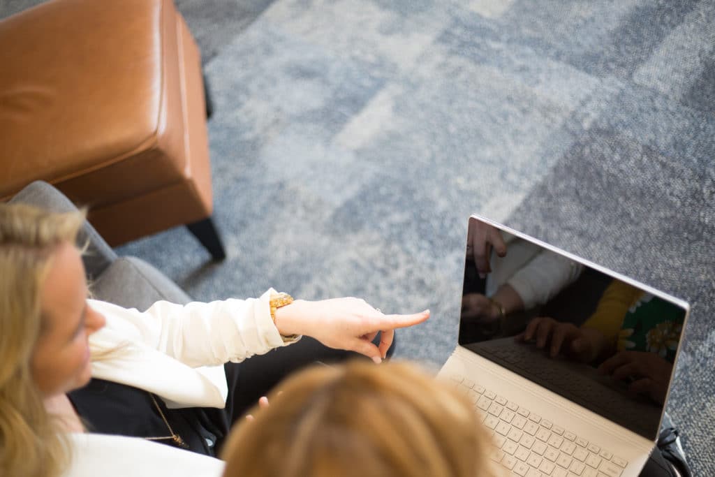 Two women sit pointing at a laptop screen, illustrating their interest in automation disruption for the insurance industry.